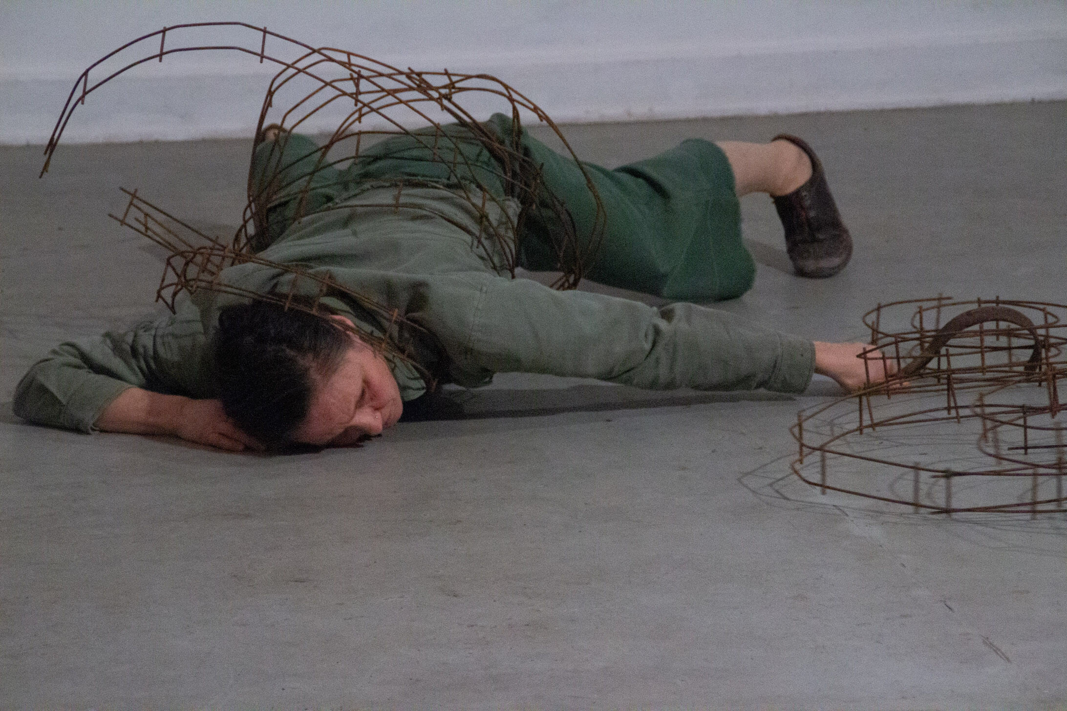 artist lying under weight of metal tracks