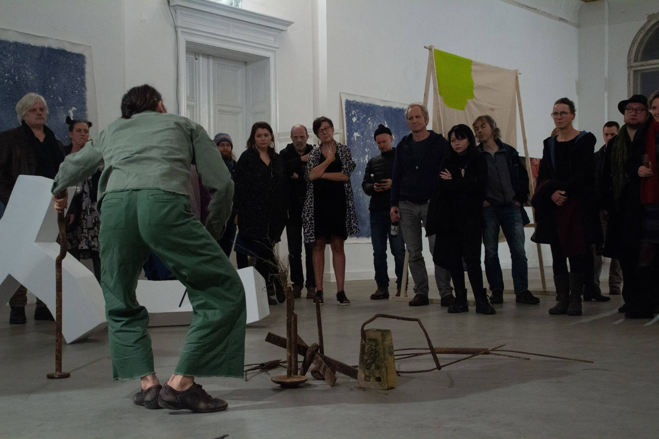 artist performing infront of audience with objects on floor
